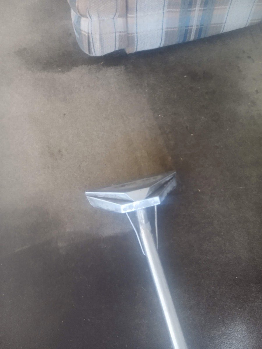 A cleaning wand on gray carpet, the carpet lighter where it has been cleaned