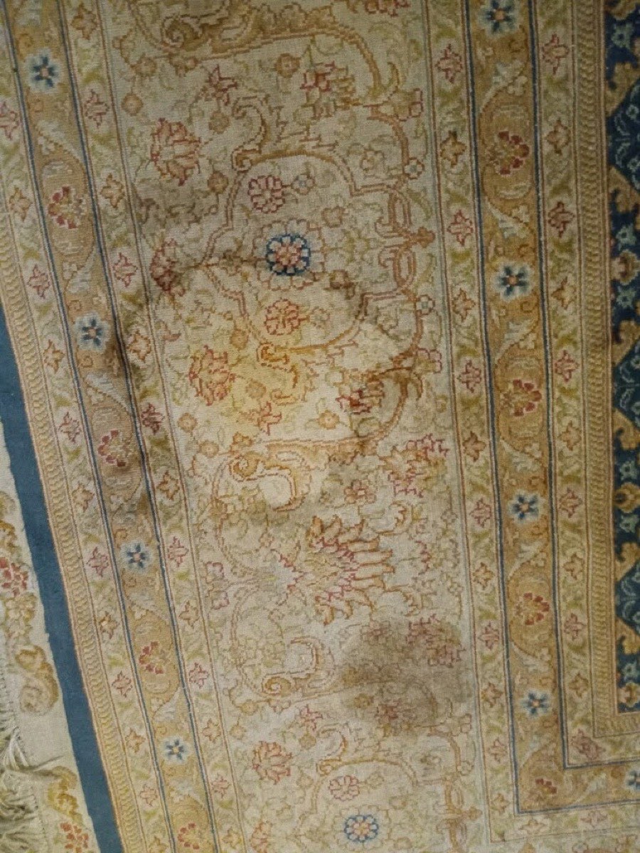 A patterned wool rug with dark stains and soiling