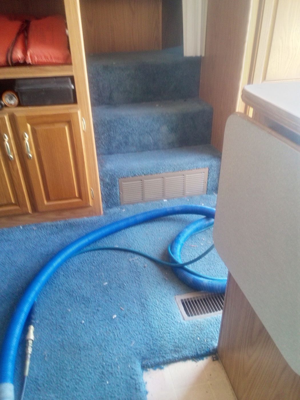 Blue carpeted stairs with a cleaning hose