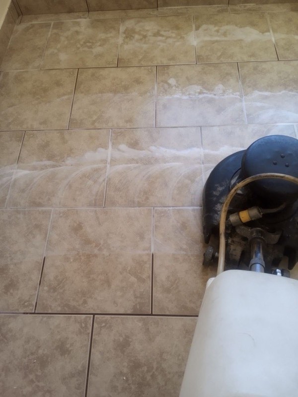 A rotary tile cleaning machine working across beige tile